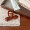 Close-up of elegant amber brown bow hair claw clip on a woven mat with warm lighting - Round Bow Claw Clip / Standard Spec
