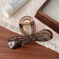 Detail view of amber brown acrylic bow hair claw clip with a strong gold metal spring - Transparent Black Bowknot