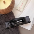 Detail of matte black rectangular hair claw clip shown in a cozy aesthetic home setting - Matte Black