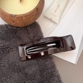 Detail of glossy chocolate brown hollow rectangular hair claw clip on cozy textured surface - Chocolate