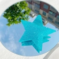 Detail einer hellblauen Stern-Haarklammer mit Glitzer-Finish und Außenreflexionen - Blau und Grün
