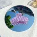 Dettaglio della grande pinza per capelli in acetato viola marmorizzato riflessa su uno specchio - Frammento di Mirtillo Trasparente