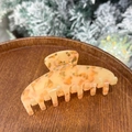 Detailed view of amber marble texture on large hair claw clip in a wooden tray - Mango Pomelo Sago