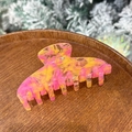 Detailed view of large marbled iridescent acetate hair claw on a decorative wooden tray - Pink Yellow Feather