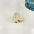 Macro view of cream acetate hair claw clip featuring white dots and golden wave patterns - Marble Beige (Small)