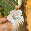 Pinza de pelo floral de acetato con perla central y diamantes de colores en mano - Flor de Perla de Alto Brillo / Concha Blanca