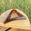 Detail of a large amber tortoiseshell hair claw clip with a strong metal spring on wood - approx. 11.5cm / Glossy Light Tortoiseshell Triangle