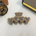 Dettaglio di una pinza per capelli in acetato marrone caffè con quattro cuori - Cachi