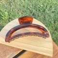 Detail view of large crescent hair claw clip in tortoiseshell resin on wooden tray - 12cm / Matte Tortoiseshell Crescent