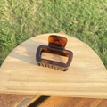Detailed view of large tortoise shell hair claw clip on a wooden stand - Approx 5.5cm / Small Glossy Light Tortoiseshell Bottle Shape