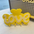 Dettaglio della molletta per capelli a cuore gialla in acetato con scritta love 3D - Grande / Giallo