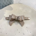 Close-up of mocha acetate bow hair clip with gold lettering on a ceramic tray - Crooked 3D Bow (Approx 9cm) / Khaki