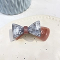 Détail de la pince à cheveux noeud en acétate marbré avec lettrage doré sur plat blanc - Gris Rose