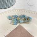 Dettaglio di un fermaglio per capelli a fiore in resina blu con cristallo su un piatto - Molletta a Becco d'Anatra Farfalla con Strass / Floreale Blu