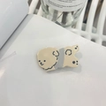 Gros plan détaillé d'une pince à cheveux chiot en acétate sur un fond de style épuré - Pull Gris Chien Beige