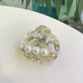 Macro shot of marble texture acetate hair claw with three elegant white pearls - Orange Texture