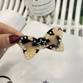 Detail of leopard print bow hair clip with pearl edges and star charm decoration - Light Tortoise Shell
