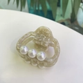 Detailed macro view of acetate hair claw with marble pattern and three white pearls - Off-White Texture