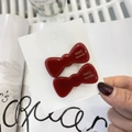Detail shot of two deep red jelly-textured bow hair clips on a white paper backing - Red