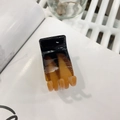 Detail of tortoiseshell patterned acrylic hair claw clip with glossy finish and metal spring - Orange-Black Gradient