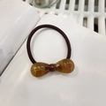 Détail de l'élastique à nœud en résine marbrée ambre avec lettrage Barrette doré - Brun Ambre