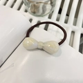 Detail of a resin bow hair tie with marble texture and high elasticity brown cord - Pearlescent White