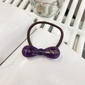 Détail d'un chouchou noeud en résine violette avec lettrage doré et élastique marron - Violet Gelée