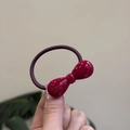 Détail d'un élastique rouge avec nœud en résine et gravure dorée Barrette la France - Rouge Vin