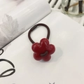 Close-up of a glossy red flower hair clip on a white magazine with artful shadows - Round Red Flower Hair Tie / Red