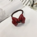 Detail of a vintage red bow hair tie with glossy finish on a white book page - Round Red Bowknot Hair Tie / Red