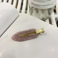 Close-up of a purple glitter resin hair clip with gold metal base on a white book page - Water Pink