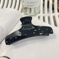 Elegante pinza per capelli in acetato nero con strass colorati su sfondo di rivista bianca - Pinza Nera con Strass Colorati