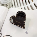 Vue détaillée d'une pince à cheveux cœur noir brillant avec strass et lettrage doré - Marron