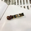 Dettaglio del fermaglio leopardato con cuore ambrato sopra un libro bianco - Stile Cuore Leopardato