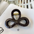 Detailed close-up of dark brown bow-shaped hair claw with gold spring mechanism - Chocolate