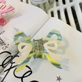 Macro detail of striped acetate bow hair claw clip with a secure golden metal spring - Striped Green Dual-Color Bowknot