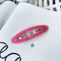 Detail of pink oval acetate hair clip with marble texture on a white vintage book page - Rose Pink Jelly