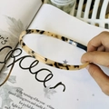 Detalle de una diadema fina con estampado de leopardo sobre una revista de moda - Estilo Carey Claro