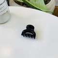 Gros plan sur une pince à cheveux noire brillante minimaliste sur une surface blanche élégante - Serrure Creuse Boucle Papillon / 4cm / Noir Brillant