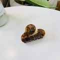 Detail view of tortoiseshell acetate hair claw clip with golden brand logo on a desk - Comma High Ponytail / 6.5cm / Blue Tortoise