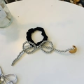 Détail d'un chouchou noir avec nœud en perles argentées et élégants pompons longs - Chouchou Long avec Nœud en Perles Argent