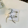Gros plan de barrettes à cheveux à nœuds argentés sur carte, accessoire élégant en métal - Pinces à Cheveux Snap avec Nœud en Ruban Noir