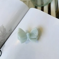 Elegant mint green acetate butterfly hair clip with gold label on white open book - Aqua Blue