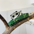 Detalle de una pinza para el pelo de panda con motivos de bambú sobre una rama de madera - Black and Dark Green