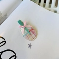 Detailed close-up of a mint green metal clip with a pink ribbon bow and floral acrylic plate - Yellow And Green Oval Striped No Mark Clip