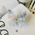 Detailed macro view of acrylic butterfly hair claw with floral pattern and golden spring - White Blue Pattern Glitter Double Layer Butterfly