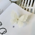 Detail shot of a white pearlescent butterfly hair claw clip with golden metal spring - Mermaid White