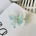 Detail of gradient blue butterfly hair claw with glitter finish on a white book - Gradient Blue White