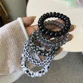Detail view of spiral telephone cord hair ties in assorted black and floral patterns - Black Sesame Style