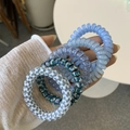 Close-up of assorted spiral telephone cord hair ties in solid colors and floral patterns - Blue Thai Milk Style